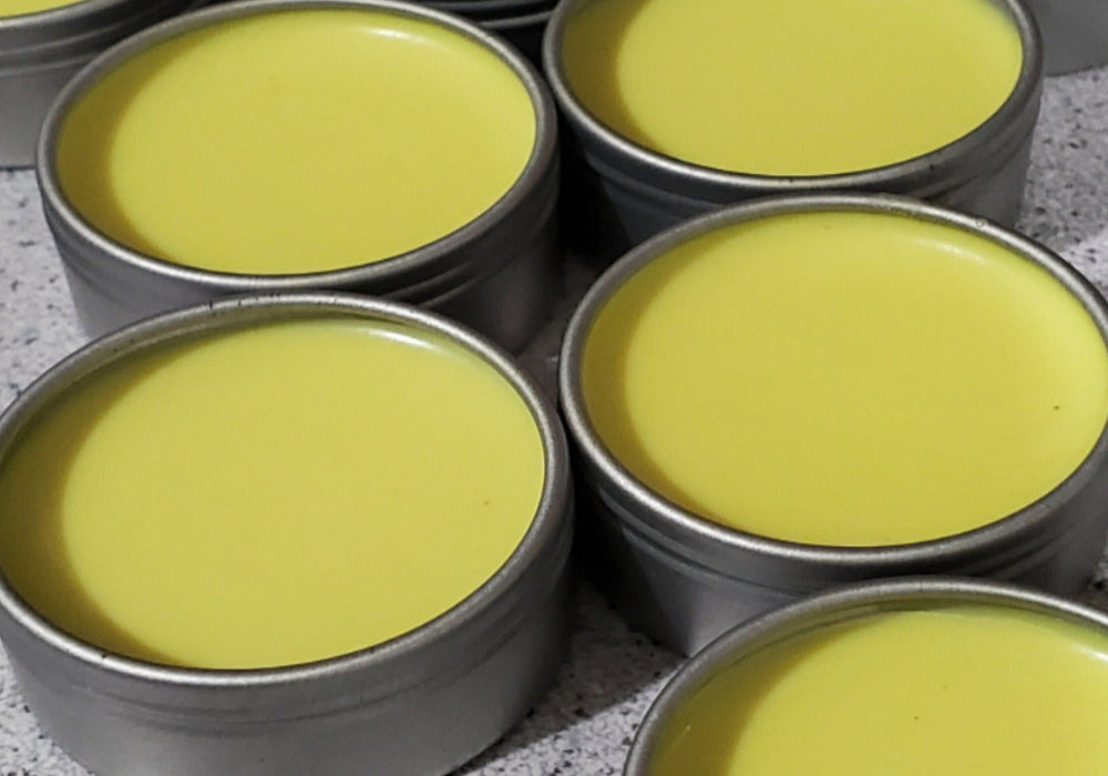 Multiple tins of yellow cream or paste on a gray surface